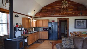 A rustic kitchen with wooden cabinets, a black refrigerator, and a wood stove. - Allure charming peaceful wooded Hill Country like views with easy Lake access (eastland)