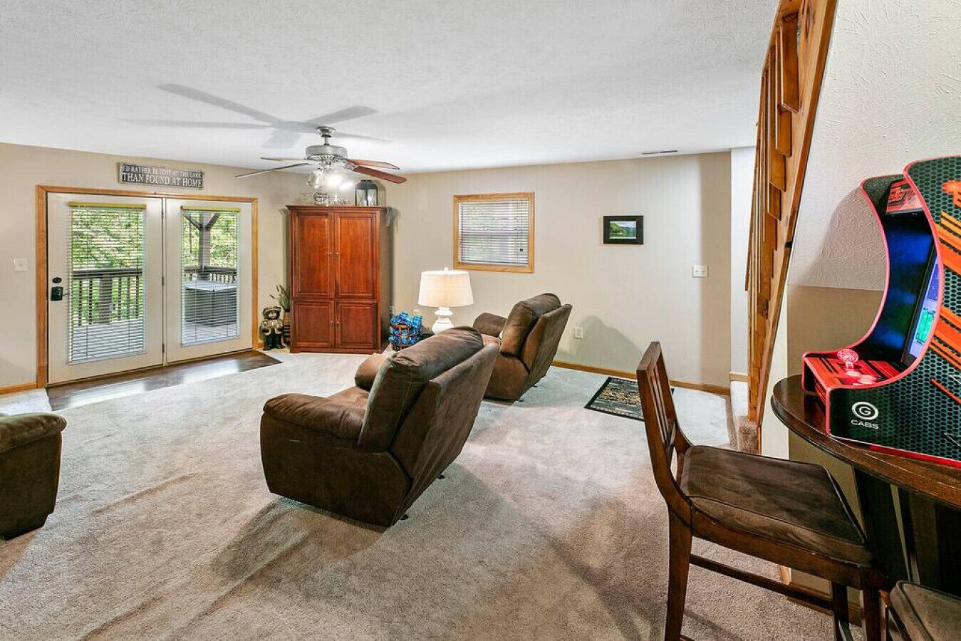 Un salon avec un ventilateur de plafond, un meuble en bois, un canapé et un fauteuil de jeu.