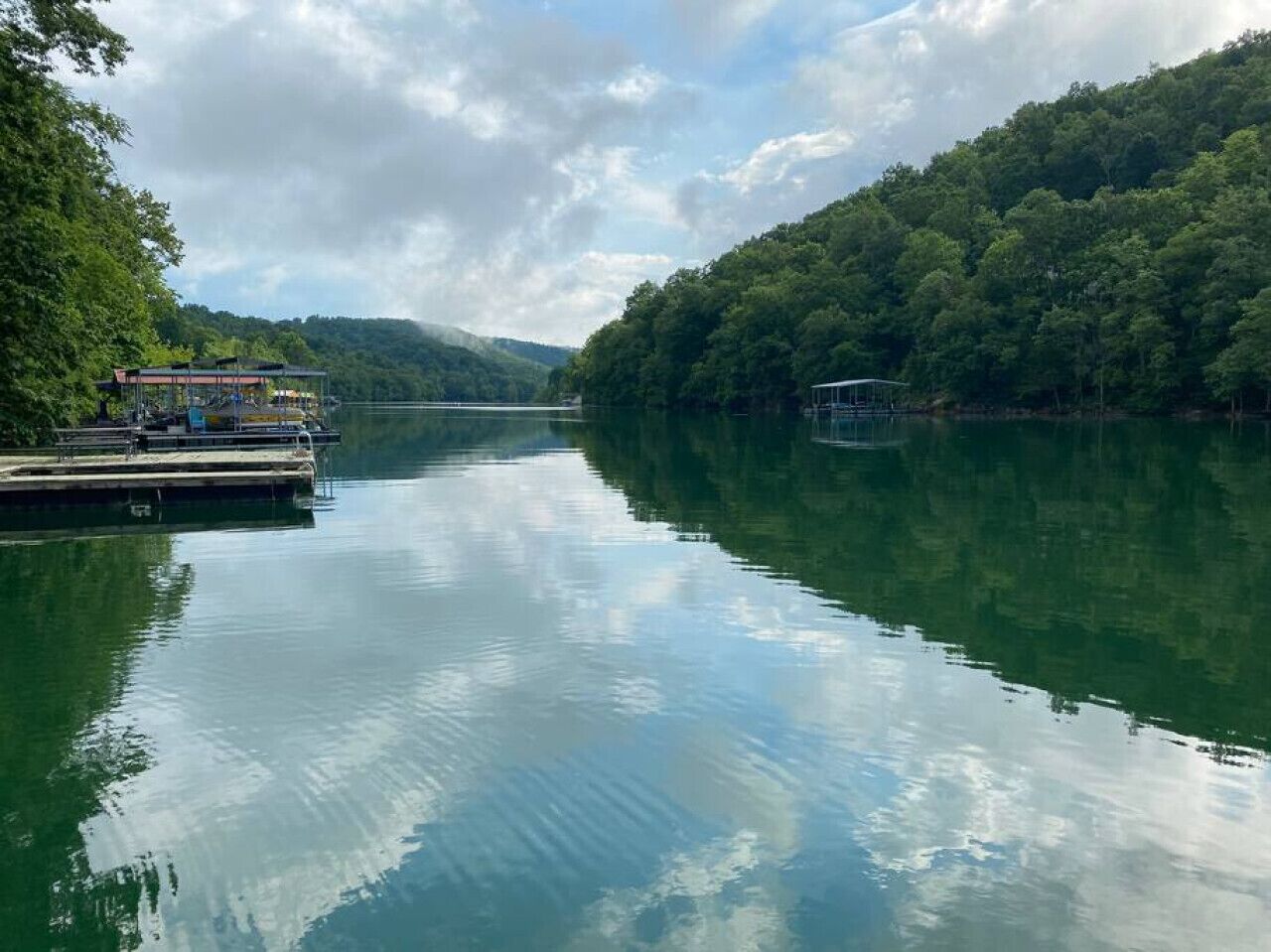 Un río tranquilo con muelles y barcos, rodeado de un bosque denso.