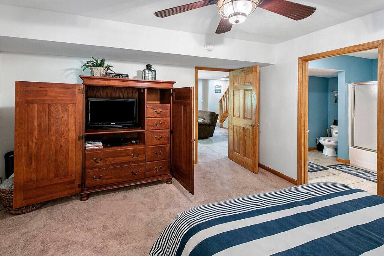 Une chambre à coucher avec une grande commode en bois, un téléviseur et une couvre-lit à rayures.