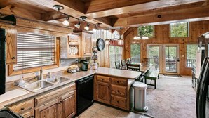 A wooden cabin-style kitchen with a sink, stove, and dining area. - Lakeside Lodge – Private Dock, Hot Tub, Fire Pit & 8 Kayaks (Speedwell)