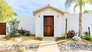 A modern house with a wooden door, surrounded by a garden with various plants and a palm tree. - Private Oasis over half an acre with private Pool & Spa. City ID 4059 (Palm Springs)
