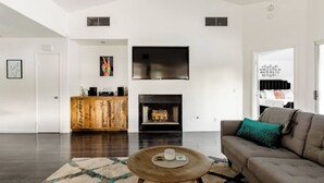 A modern living room with a fireplace, a flat-screen TV, and a wooden coffee table. - Private Oasis over half an acre with private Pool & Spa. City ID 4059 (Palm Springs)