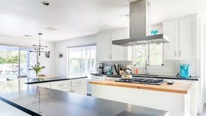 A modern kitchen with white cabinets, a large island, and a stainless steel range hood. - Private Oasis over half an acre with private Pool & Spa. City ID 4059 (Palm Springs)