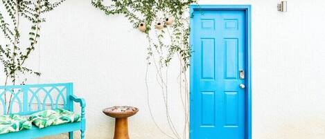 A blue door, a blue bench, and a small table with a plant.