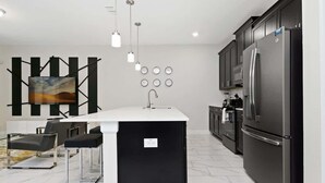 A modern kitchen with a central island, black cabinetry, stainless steel appliances, and a minimalist design. - Resort Townhome 4Bd Pool and Water Park 4841 (kissimmee)