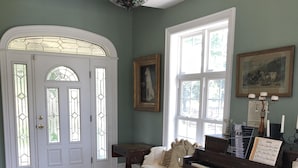 Een ruime kamer met een piano, een bank en een eettafel.
