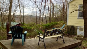 Eine Holzterrasse mit zwei Adirondack-Stühlen und einer Bank.