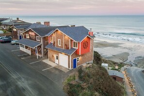 A coastal building with a red wall and a large wheel symbol, adjacent to a beach.