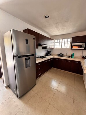 A kitchen with a stainless steel refrigerator, dark wooden cabinets, a microwave, and a gas stove. - In front of the beach with power and wifi included! (CHUBURNÁ PUERTO)