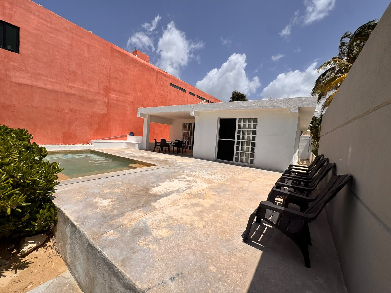 A courtyard with a pool, outdoor seating, and a building with a red facade.