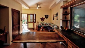 Ein Wohnzimmer mit Couch, Holztisch, Deckenventilator und einer Tür zum Garten.