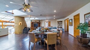 A spacious dining area with a high ceiling fan, wooden flooring, and a large window providing natural light.
