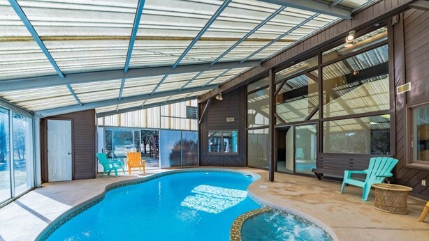 An indoor swimming pool with a glass ceiling, surrounded by wooden walls and large windows.