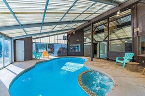 Una piscina interior con techo de vidrio, rodeada de paredes de madera y ventanas amplias.