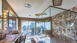 A modern kitchen with a marble countertop, a glass partition, and a view of a snowy landscape.