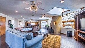 A spacious living room with a large sofa, ceiling fans, and a fireplace.