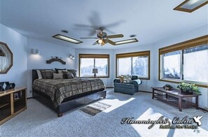 Relax in a spacious bedroom with a large bed, ceiling fan, and two windows.