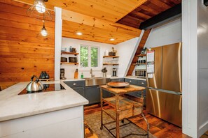 A modern kitchen with wooden accents, stainless steel appliances, and a view of the outdoors.