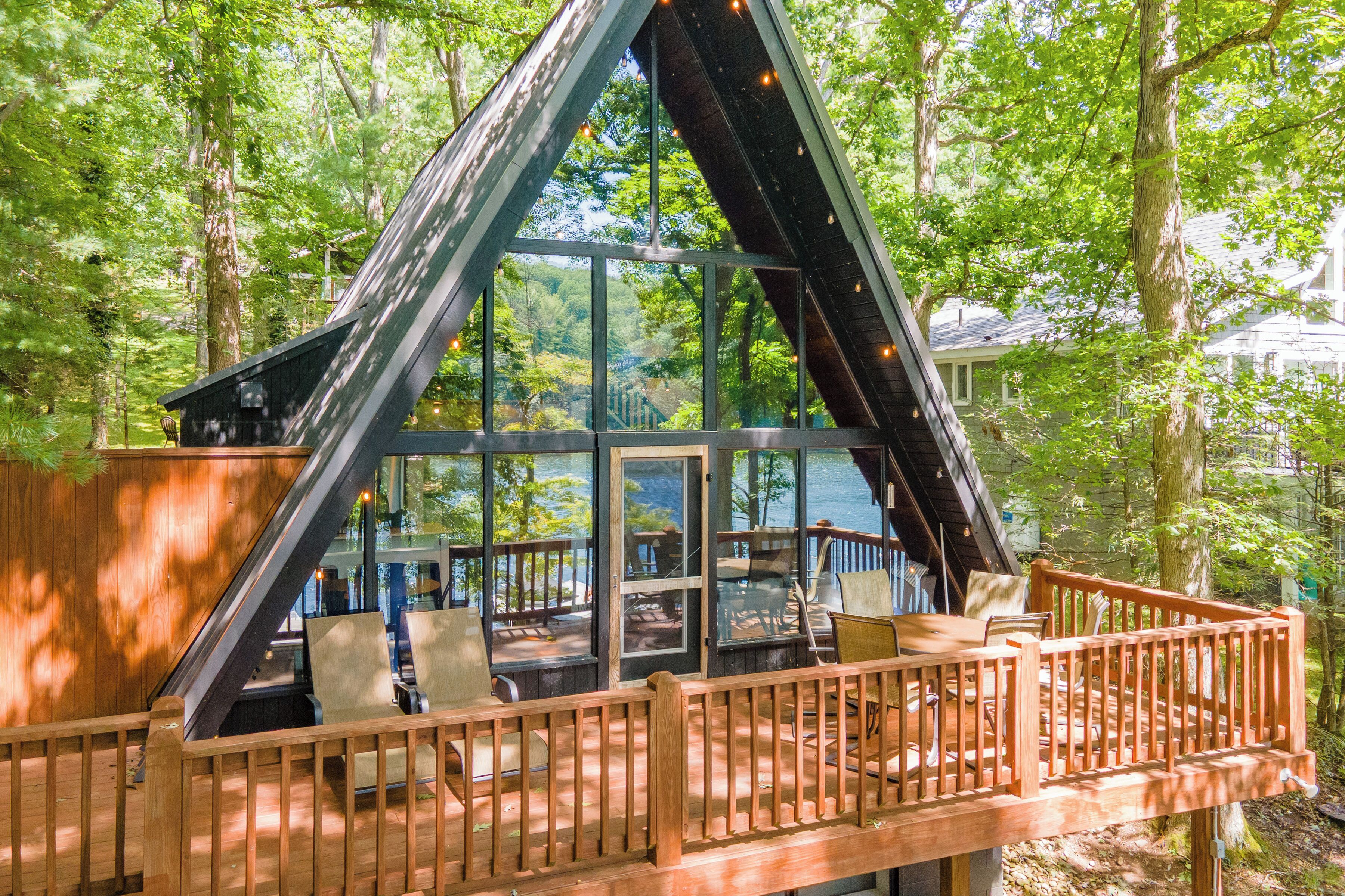 A cabin with a glass facade, wooden deck, and outdoor seating area.