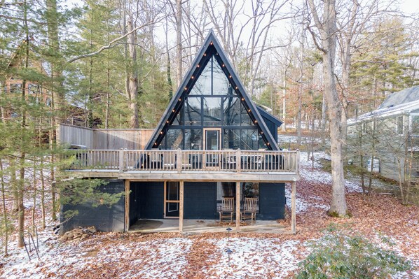 A cabin with a balcony, wooden deck, and a glass front.