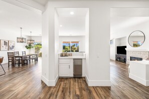 A modern kitchen with white cabinetry, a built-in dishwasher, and a view to the outdoors.