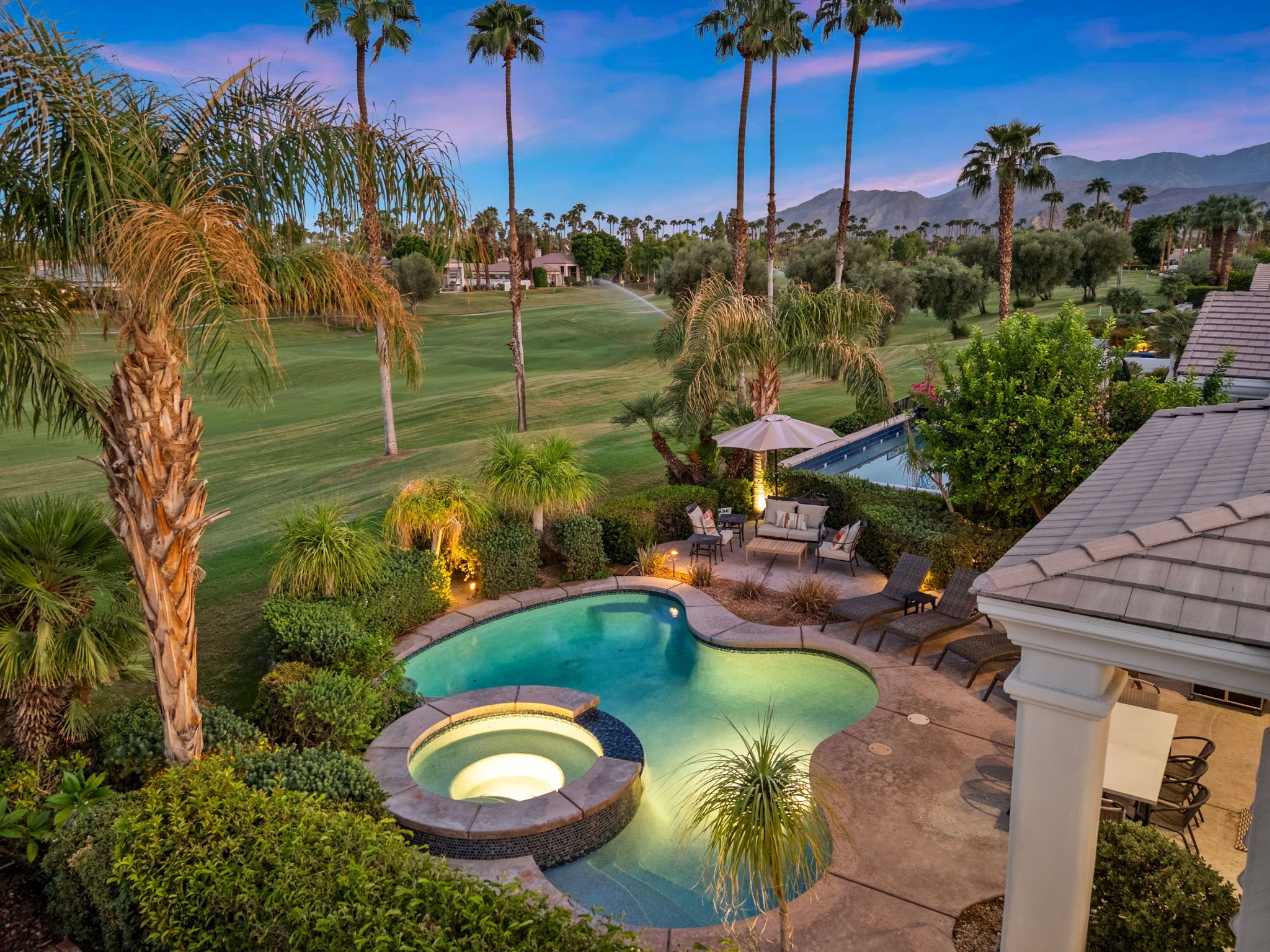 A residential area with a swimming pool, patio furniture, and a view of a golf course.