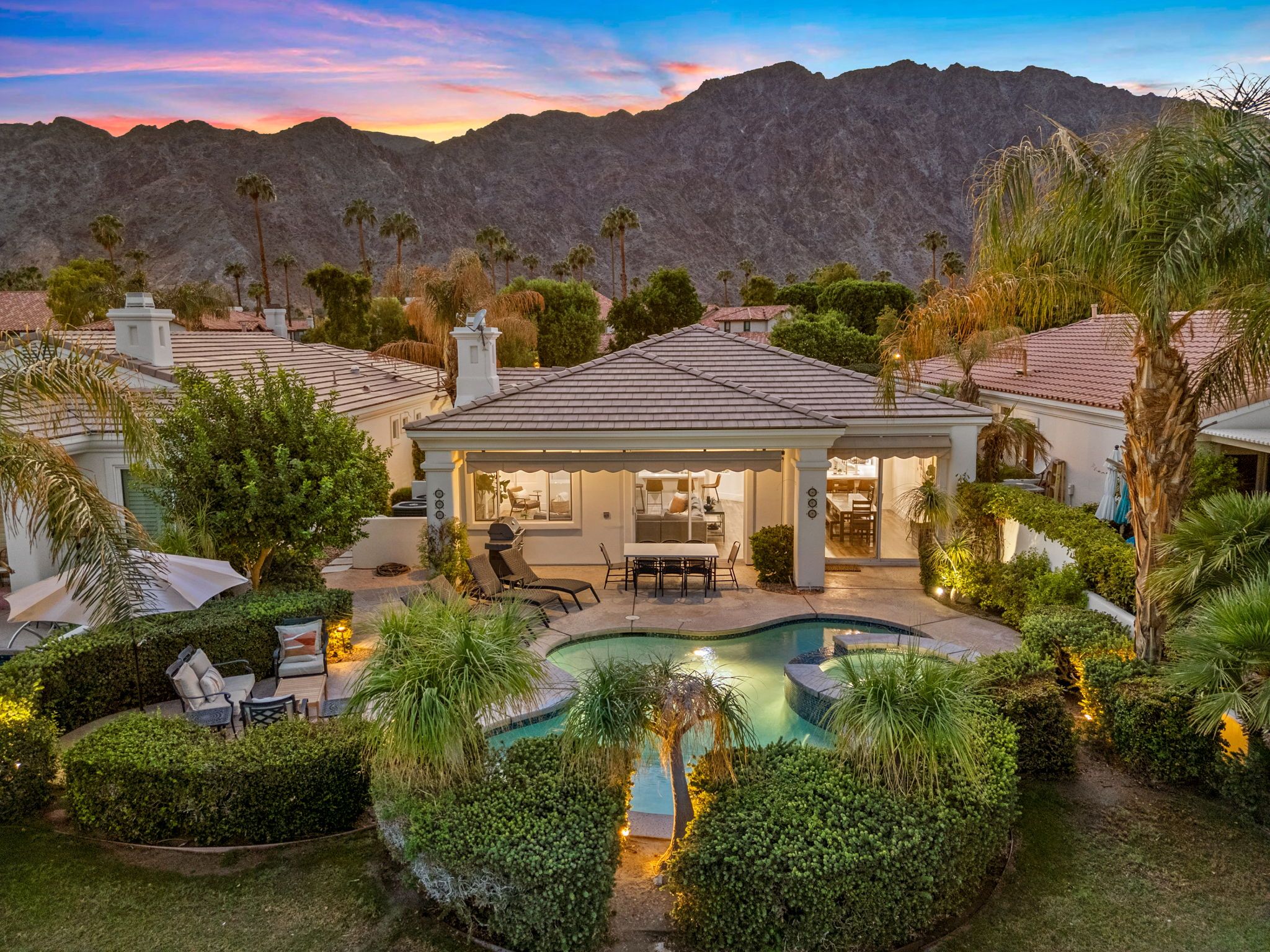 A residential property with a swimming pool, patio furniture, and a view of mountains.