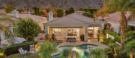 A residential property with a swimming pool, patio furniture, and a view of mountains.