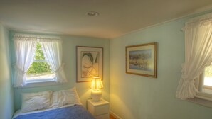 A bedroom with a bed, a nightstand, a lamp, and two framed pictures on the wall.