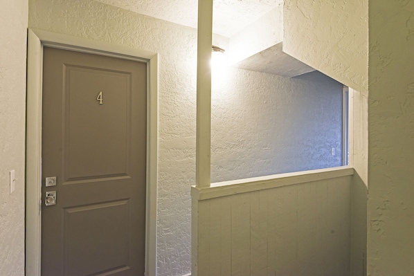 A door with the number 4, a textured wall, and a window with a view of the outside.