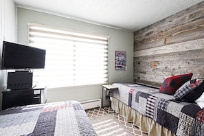 A bedroom with two beds, a TV, and a poster on the wall.