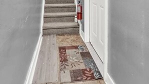 A staircase with a carpeted floor, a fire extinguisher, and a door at the top. - Open Flat by Park & Metro (Philadelphia)
