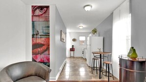 A modern kitchen with a bar area, a large painting on the wall, and a leather chair. - Open Flat by Park & Metro (Philadelphia)