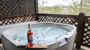 Een hottub met een fles Duplu en twee glaasjes op een houten dienblad.