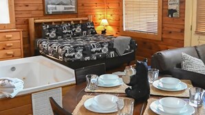 Een gezellig, houten ingerichte kamer met een bed, een eettafel en een bad.