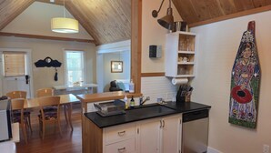 A kitchen with wooden cabinets, a black countertop, and a dining area with chairs. - Exquisite 1-Bedroom House on North Church Ave (Bozeman)