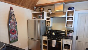 A compact kitchen with a stainless steel refrigerator, a gas stove, and a built-in oven. There is a wooden countertop and a black sink with a dish rack. - Exquisite 1-Bedroom House on North Church Ave (Bozeman)