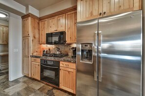 A kitchen with wooden cabinets, a stainless steel refrigerator, a microwave, a coffee maker, and a stove. - Private Desert Sunset Getaway (Santa Clara)