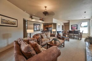 A spacious living room with a large brown sofa set, a dining table with chairs, and a kitchen area visible through an open doorway. - Private Desert Sunset Getaway (Santa Clara)