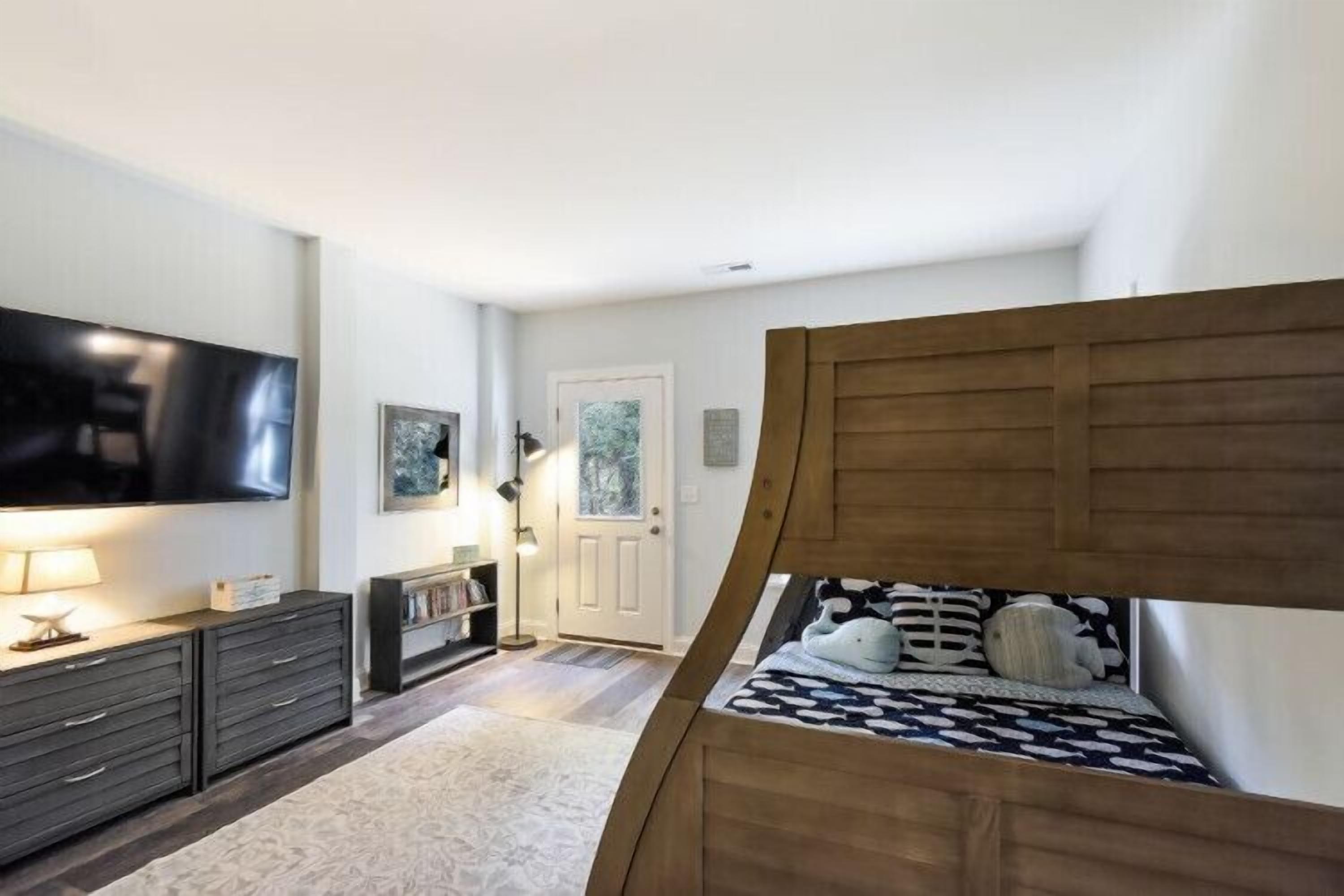 Un dormitorio con cama, televisión, cómoda y puerta.