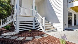 A white house with a porch and a staircase leading to the entrance. - Updated and Modern Corolla Beach Retreat! (Corolla)