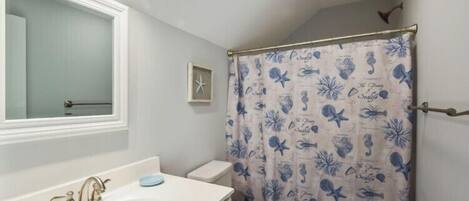 A bathroom with a white sink, a toilet, and a shower curtain with a floral pattern.