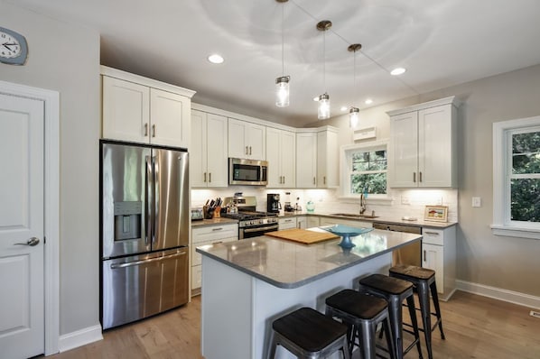 Enjoy cooking in this well-equipped kitchen with a central island, bar stools, stainless steel appliances, and ample counter space.