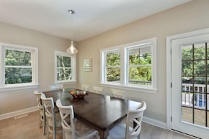A dining area with a dark wooden table, white chairs, and a hanging light fixture.