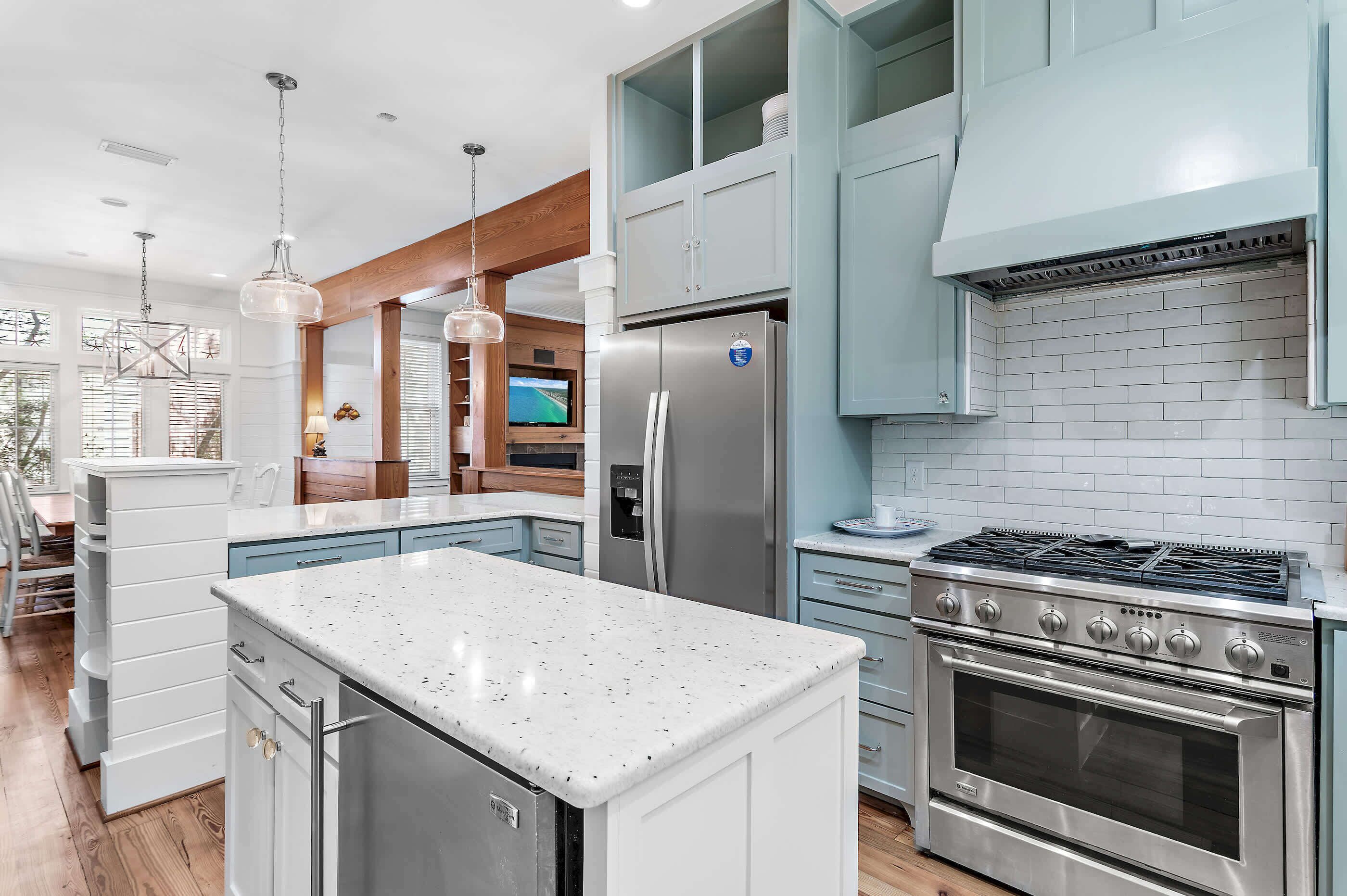 A modern kitchen with stainless steel appliances, a central island, and light blue cabinetry.