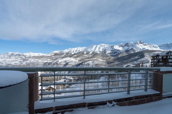 A mountain landscape with snow-covered peaks and a wooden building in the foreground.