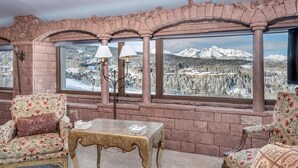 A cozy seating area with a table, two chairs, and a view of snow-covered mountains through large windows. - Unbeatable Views in 3 Bedroom Penthouse - Great Location (Mountain Villlage)