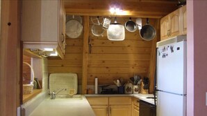 Una cocina compacta con armarios de madera, un lavamanos y un refrigerador.