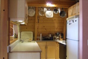 Eine kleine Küche mit Holzausstattung, Spüle und Kühlschrank.